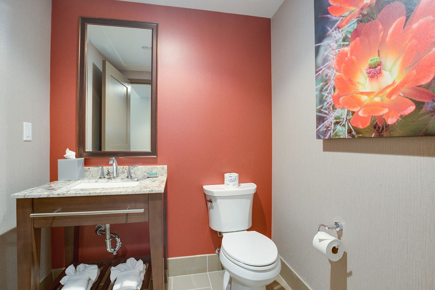 Ein Badezimmer mit Marmorwaschbecken, Toilette und einem großen Blumenbild an der Wand.
