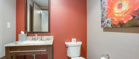 Ein Badezimmer mit Marmorwaschbecken, Toilette und einem großen Blumenbild an der Wand.