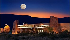 Ein Gebäude mit der Beschilderung 'Cliff Castle Casino', ein auffälliger Mond am Himmel und eine gebirgige Kulisse.