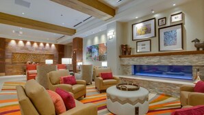 Een ruime zithoek met meerdere beige fauteuils, een centraal voetenbankje en een groot aquarium.
