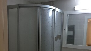 A bathroom with a glass shower enclosure, a sink, and a mirror above it. - Tuyap Apartments (Istanbul)
