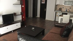 A modern living room with a flat-screen TV, a leather sofa, and a coffee table. - Tuyap Apartments (Istanbul)