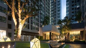 A modern hotel courtyard with a geometric light installation, a water feature, and a building with large windows. - The base pattaya condo (Pattaya)