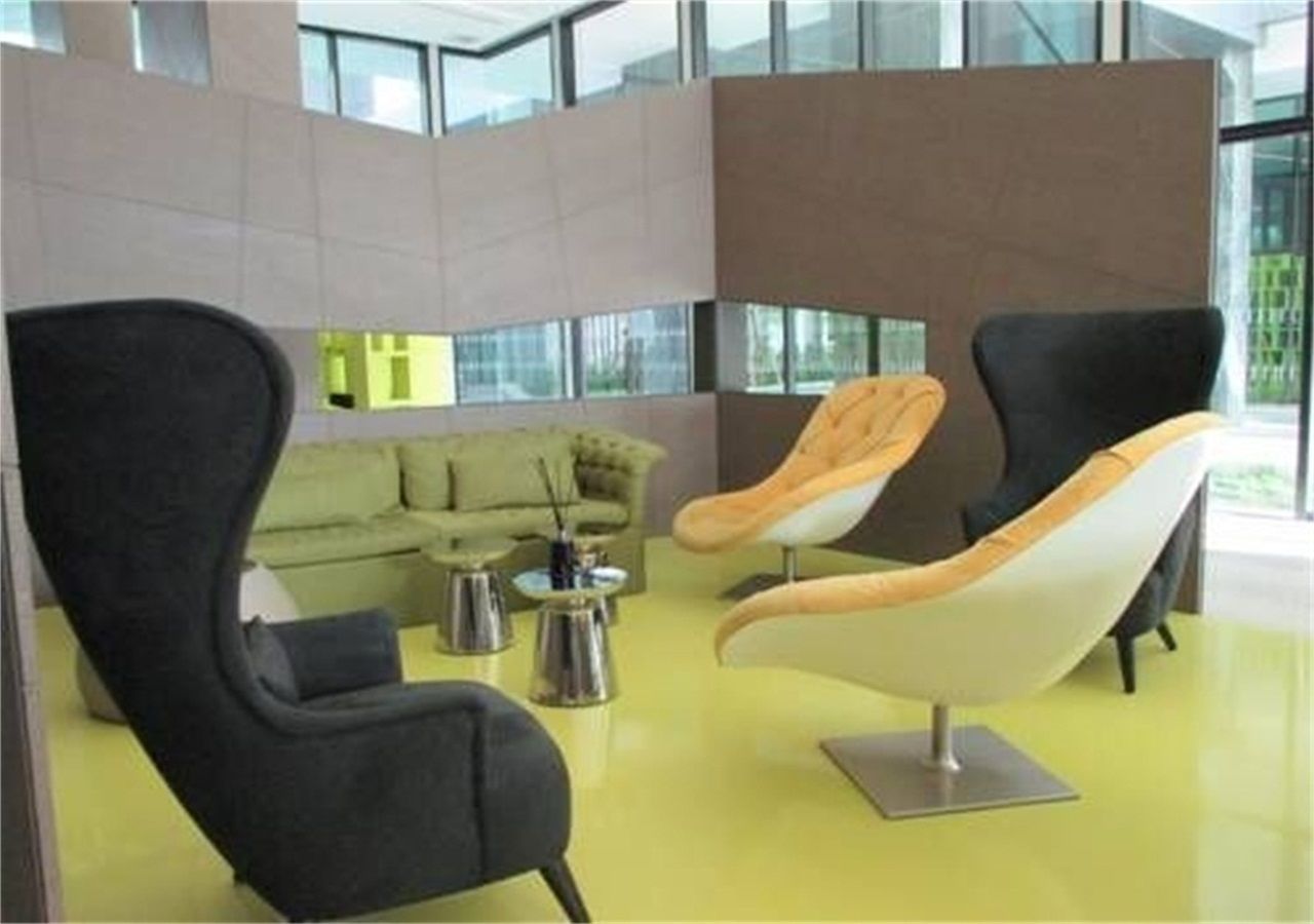 A modern lounge area with black and white chairs, a green sofa, and a yellow floor.
