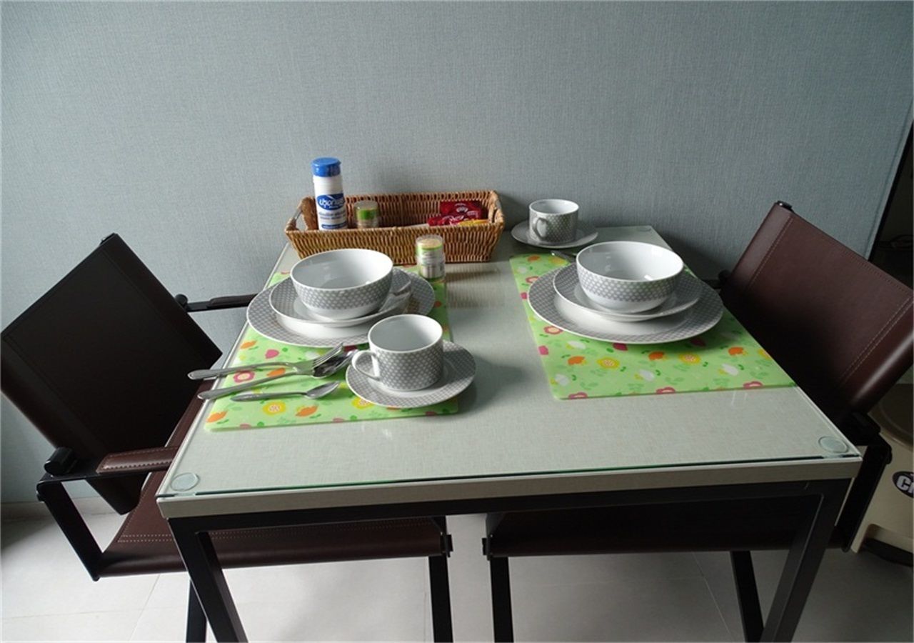 Mesa lista con platos, tazones y tazas, junto con una cesta y una botella.