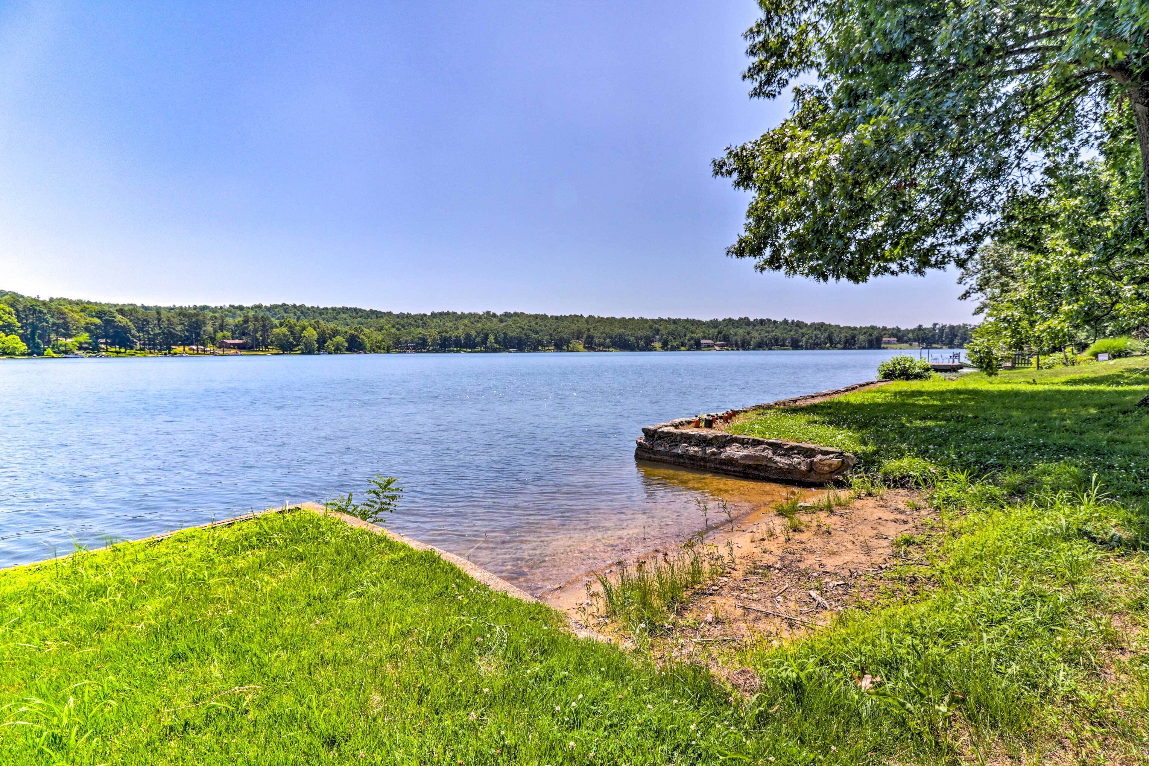Une vue sur le lac, avec une zone herbeuse et une jetée en bois qui s’avance dans l’eau.