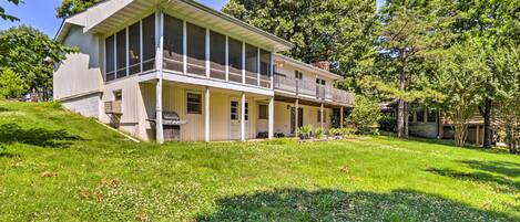 A two-story house with a large front porch, a screened porch on the upper floor, and a well-maintained lawn.