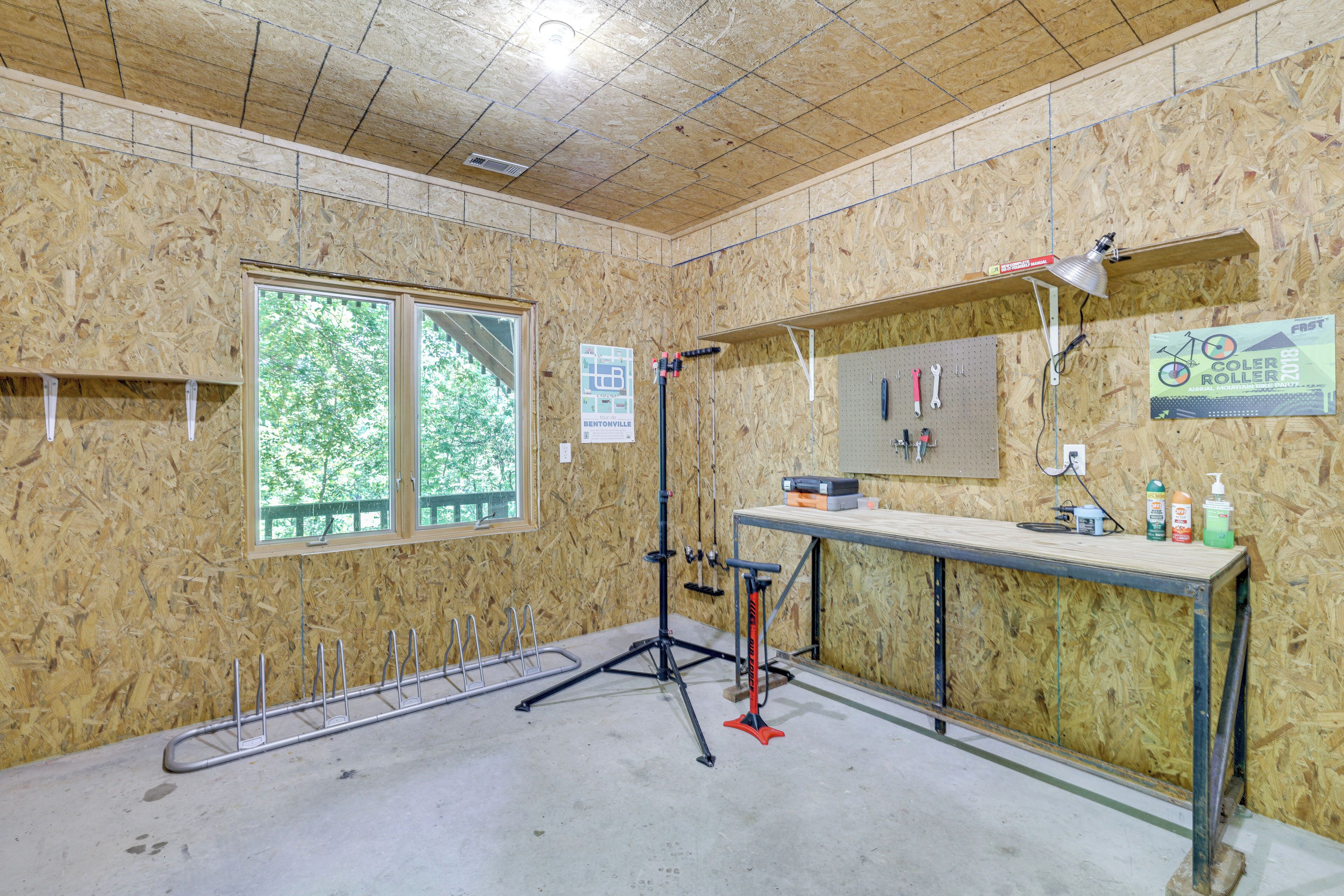 Una habitación con un ventanal grande, un banco de trabajo y un tablero de corcho con herramientas.
