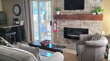 Un salon avec un mur en pierre, une cheminée, un téléviseur et un canapé.