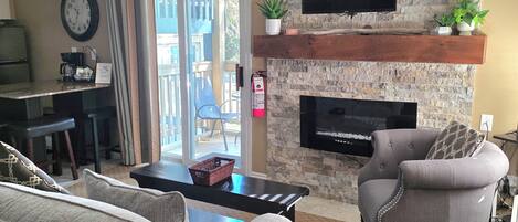 A living room with a stone wall, a fireplace, a television, and a sofa.