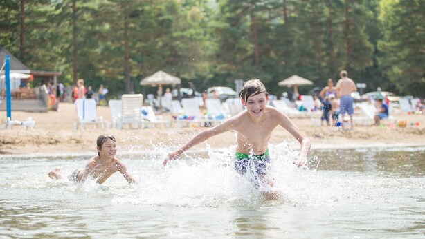 A beach scene with people swimming and playing in the water.