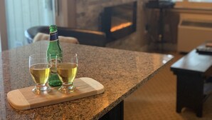 A kitchen counter with a bottle of liquor and two glasses on a wooden board.