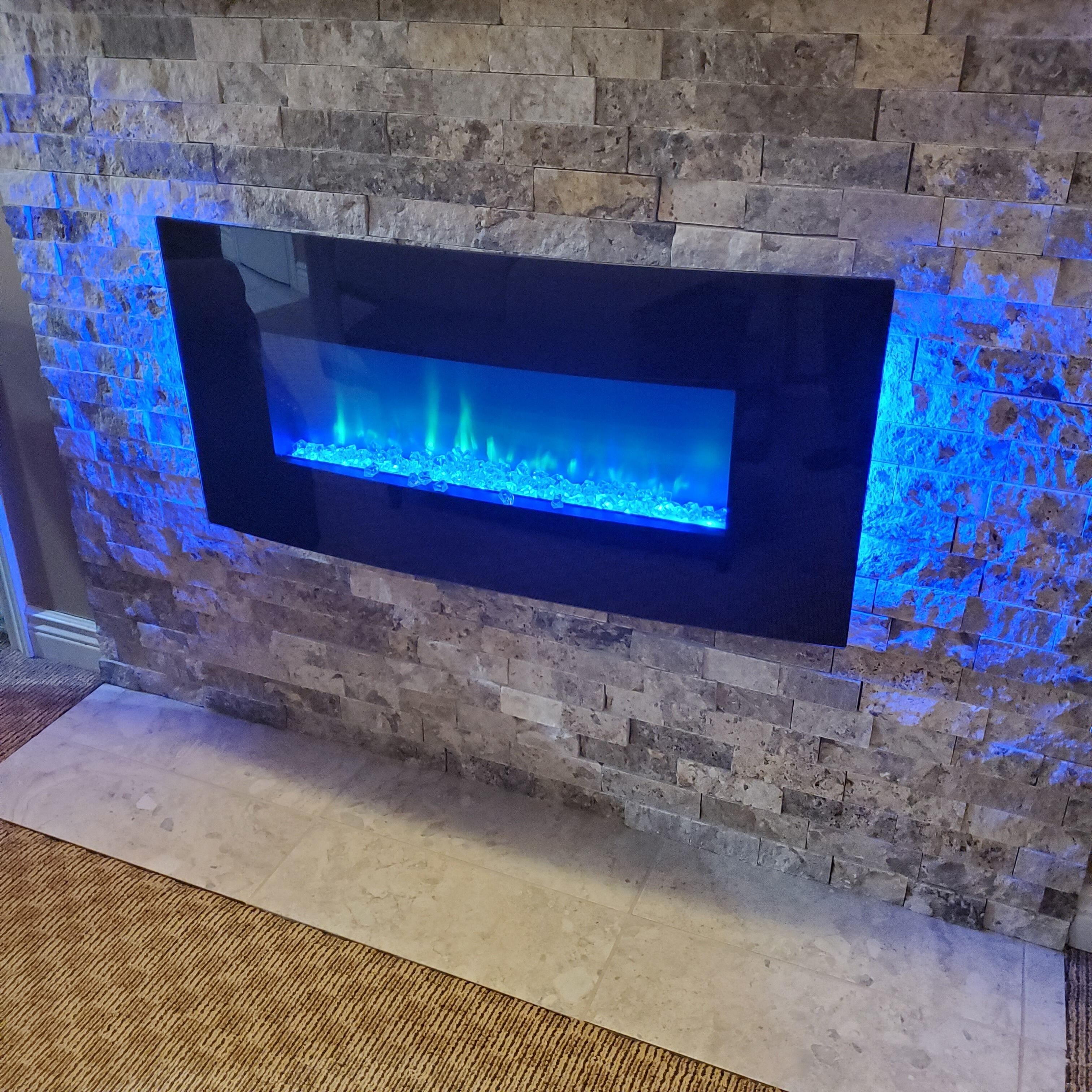 Un muro de piedra con una fuente rectangular iluminada.
