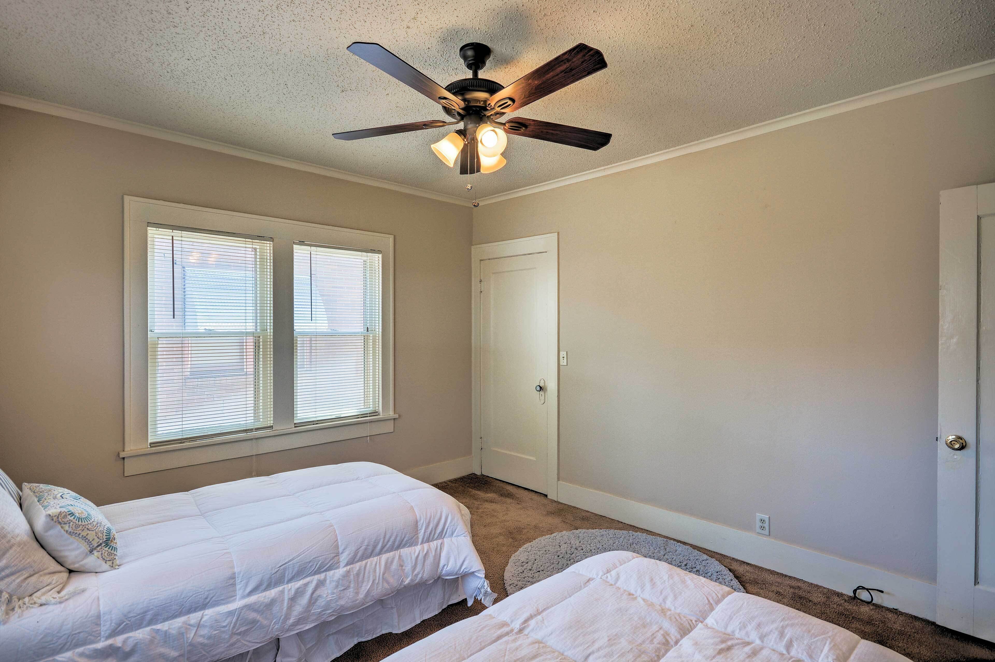 Ein Schlafzimmer mit zwei Einzelbetten, einem Deckenventilator und einer Tür mit Fenster.