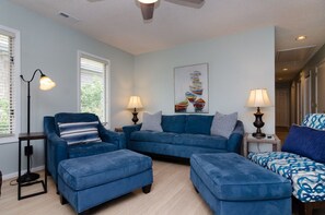 Ein Wohnzimmer mit einem blauen Sofagarnitur, zwei Beistelltischen mit Lampen und einem Bild an der Wand.