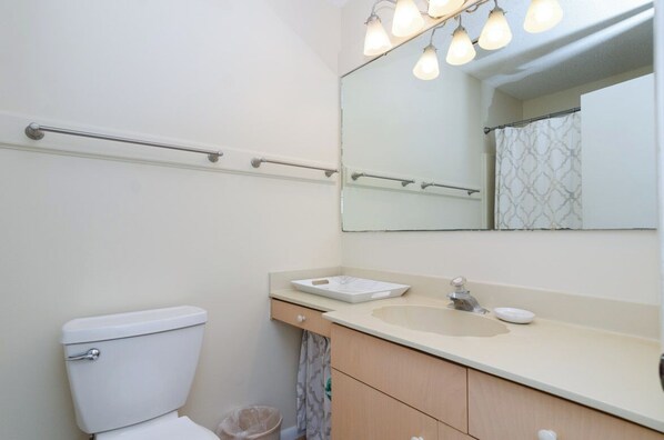 Un baño con inodoro, lavabo, espejo y toallero.
