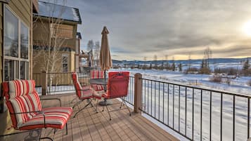 A deck with outdoor furniture and a view of a snowy landscape.