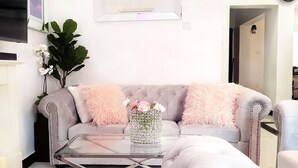 A living room with a tufted sofa, a glass coffee table, and a vase with flowers.