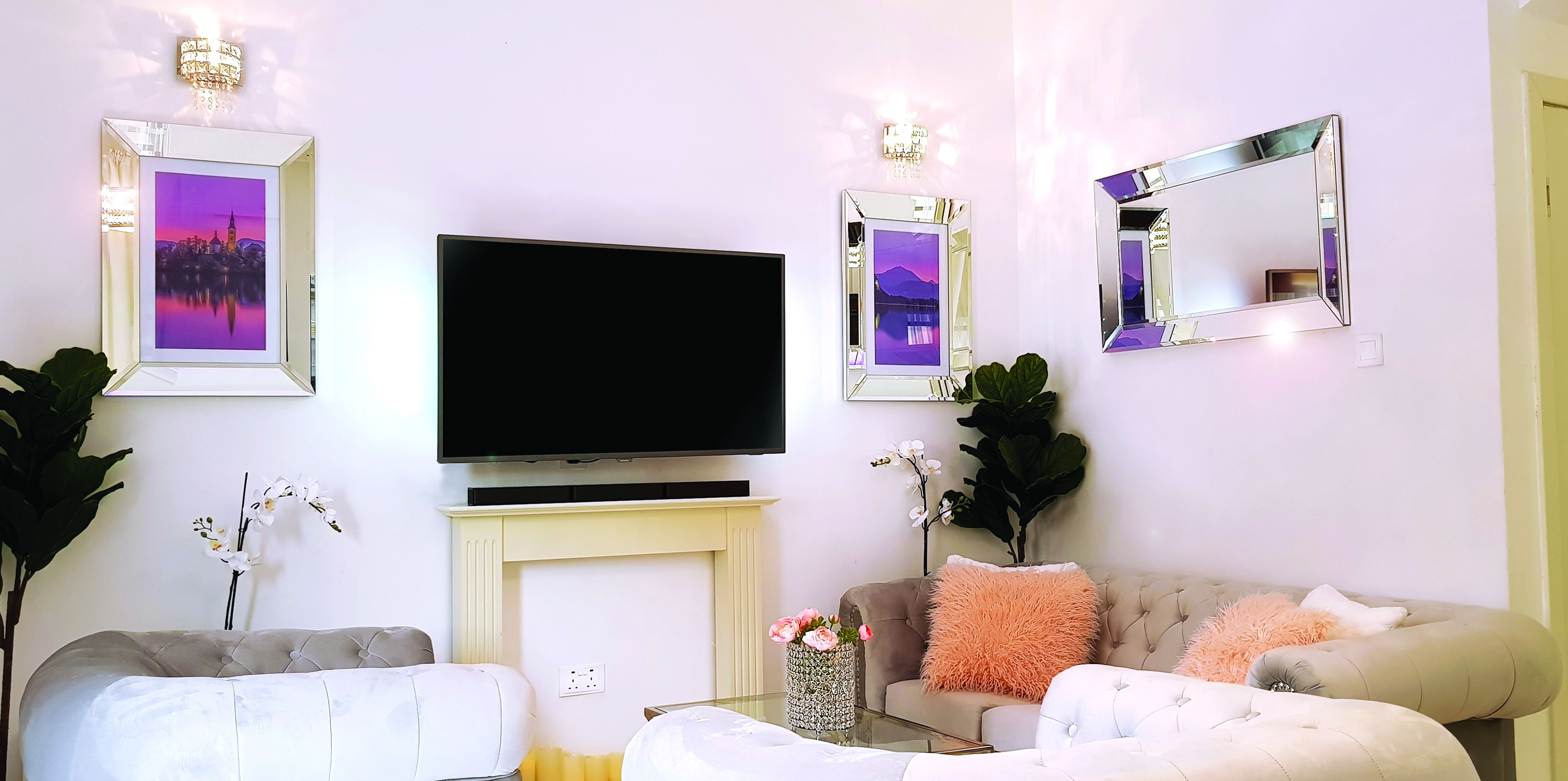 A living room with a flat-screen TV, two framed pictures, a fireplace, and a sofa.