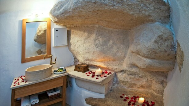 A bathroom with a stone wall, a wooden vanity, a mirror, and a lit candle. - Private villa with private pool and amazing view in an unspoilt environment (Rethymno)