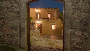 A stone archway leading to a traditional house with a courtyard, a stone wall, and a sign above the archway. - Private villa with private pool and amazing view in an unspoilt environment (Rethymno)