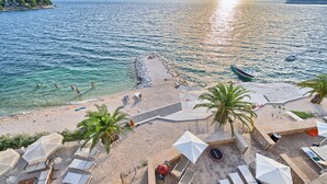 A beach with sun loungers, umbrellas, and a view of the sea. - Beachfront Villa Deep Blue with Pool I (Trogir)