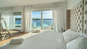 A bedroom with a large bed, white curtains, and a view of a beach and sea. - Beachfront Villa Deep Blue with Pool I (Trogir)