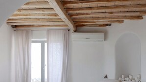 A bedroom with a curved bed, a skylight, and a wooden ceiling. - Villa DeLucien (Mykonos)