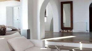 A modern interior with a wooden ceiling, white walls, and an arched doorway. - Villa DeLucien (Mykonos)