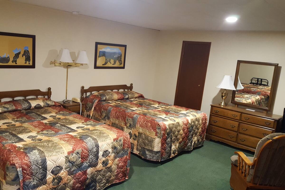 Ein Hotelzimmer mit zwei Betten, einem Schminktisch, einem Sessel und zwei Wandleuchten.