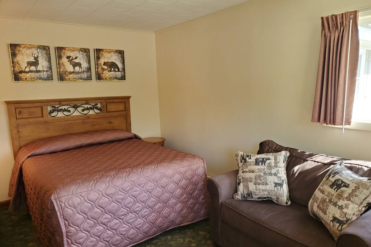 Ein Zimmer mit einem Bett, einer Couch und drei an der Wand hängenden Tierbildern.