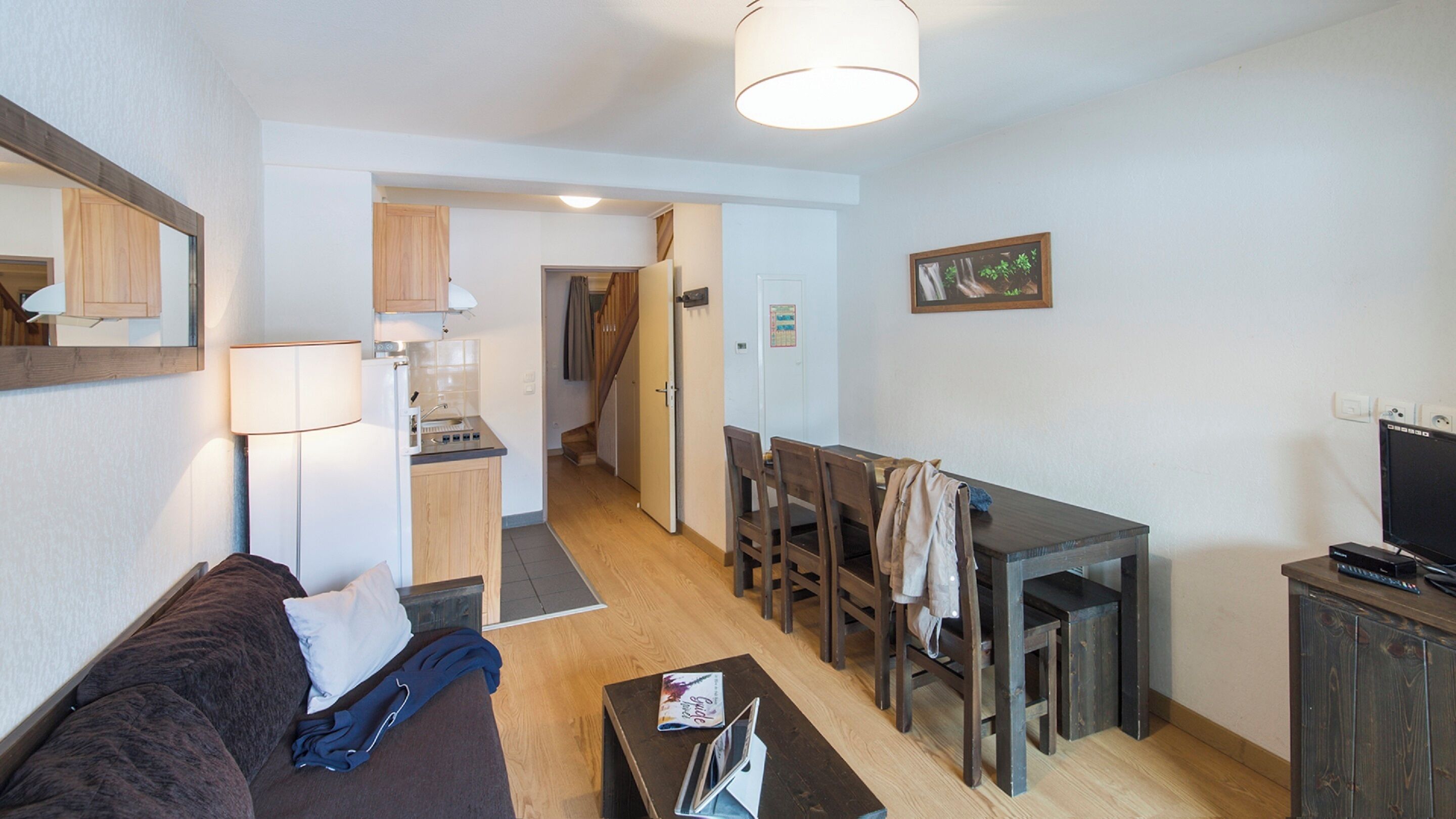 Un espace de vie compact comprenant un canapé, une table à manger, un téléviseur et un coin cuisine.