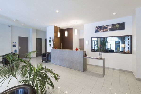 A modern reception area with a reception desk, seating, and a large window with a view. - Les Jardins de Balnea Loudenvielle 4PD10 (Loudenvielle)