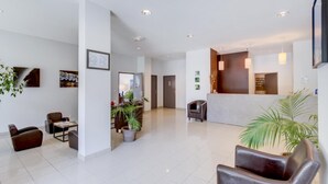 A spacious lobby with a reception desk, seating area, and potted plants. - Les Jardins de Balnea Loudenvielle 4PD10 (Loudenvielle)