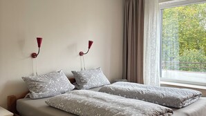 A double bed with patterned bedding, a wooden headboard, and two wall-mounted lamps.