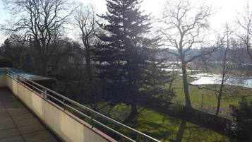 Ein Balkon mit Blick auf einen Park und ein Gewässer.