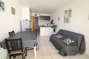 Un espace de vie compact comprenant une table à manger, des chaises, un canapé et un coin cuisine.