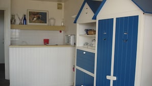 Eine Küche mit einer weißen Arbeitsplatte, einem blauen Schrank und einem roten Wasserkocher.
