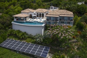 A large house with a swimming pool, solar panels, and lush greenery. - Stunning views! Infinity pool. 5* South Shore home. (Cruz Bay)