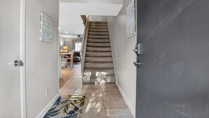 A hallway with a carpeted staircase leading to a dining area with a table and chairs. - Surf Court 30 - Updated 2 Bedroom Condo - Short Walk to Beach (Hilton Head Island)