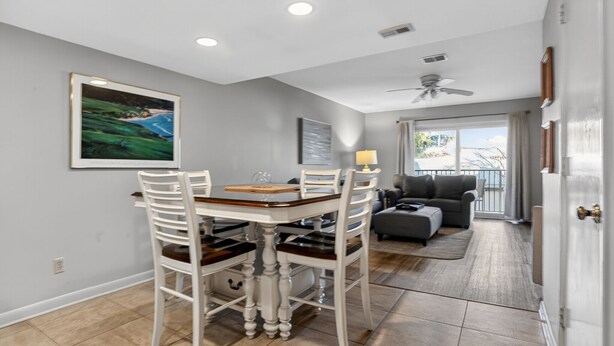 A dining area with a table and chairs, a ceiling fan, and a view to a balcony. - Surf Court 30 - Updated 2 Bedroom Condo - Short Walk to Beach (Hilton Head Island)