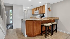 A kitchen with wooden cabinets, a granite countertop, and a microwave. - Surf Court 30 - Updated 2 Bedroom Condo - Short Walk to Beach (Hilton Head Island)