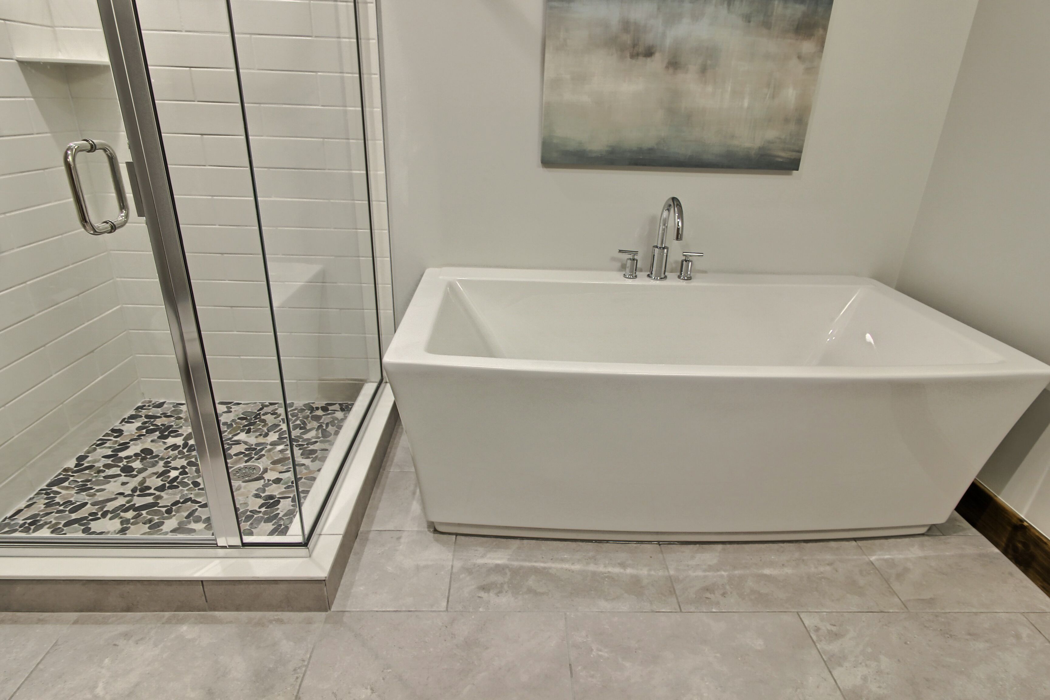 Un baño moderno con una bañera independiente, ducha con mampara de vidrio y suelo de baldosas.