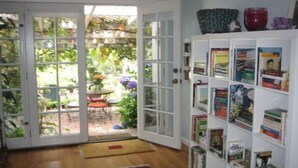 A room with a bookshelf, a door leading to a garden, and a patterned rug.