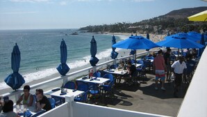 A seaside restaurant with outdoor seating overlooking the ocean.