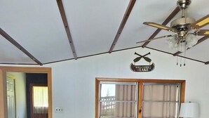 Ein Wohnzimmer mit einer Couch, einem Holztisch, einem Deckenventilator und einem Fenster mit Vorhängen.