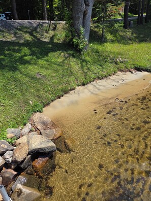 Un arroyo cristalino con rocas y una zona cubierta de césped.