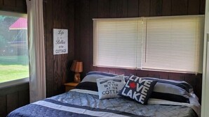 Ein Schlafzimmer mit einem Bett, einem Fenster mit Jalousien, einer Lampe und einem Schild an der Wand.