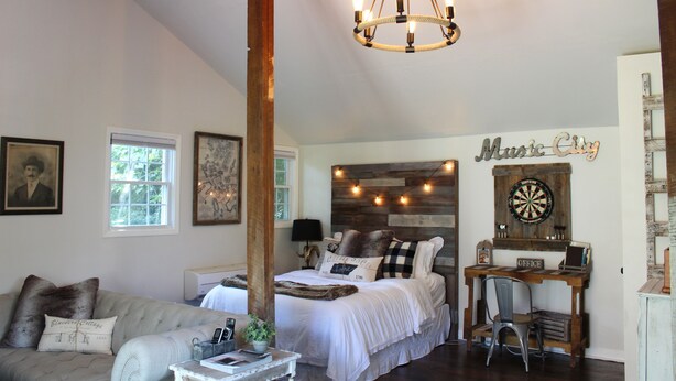 Un dormitorio con cama, escritorio, silla, sofá y candelabro.