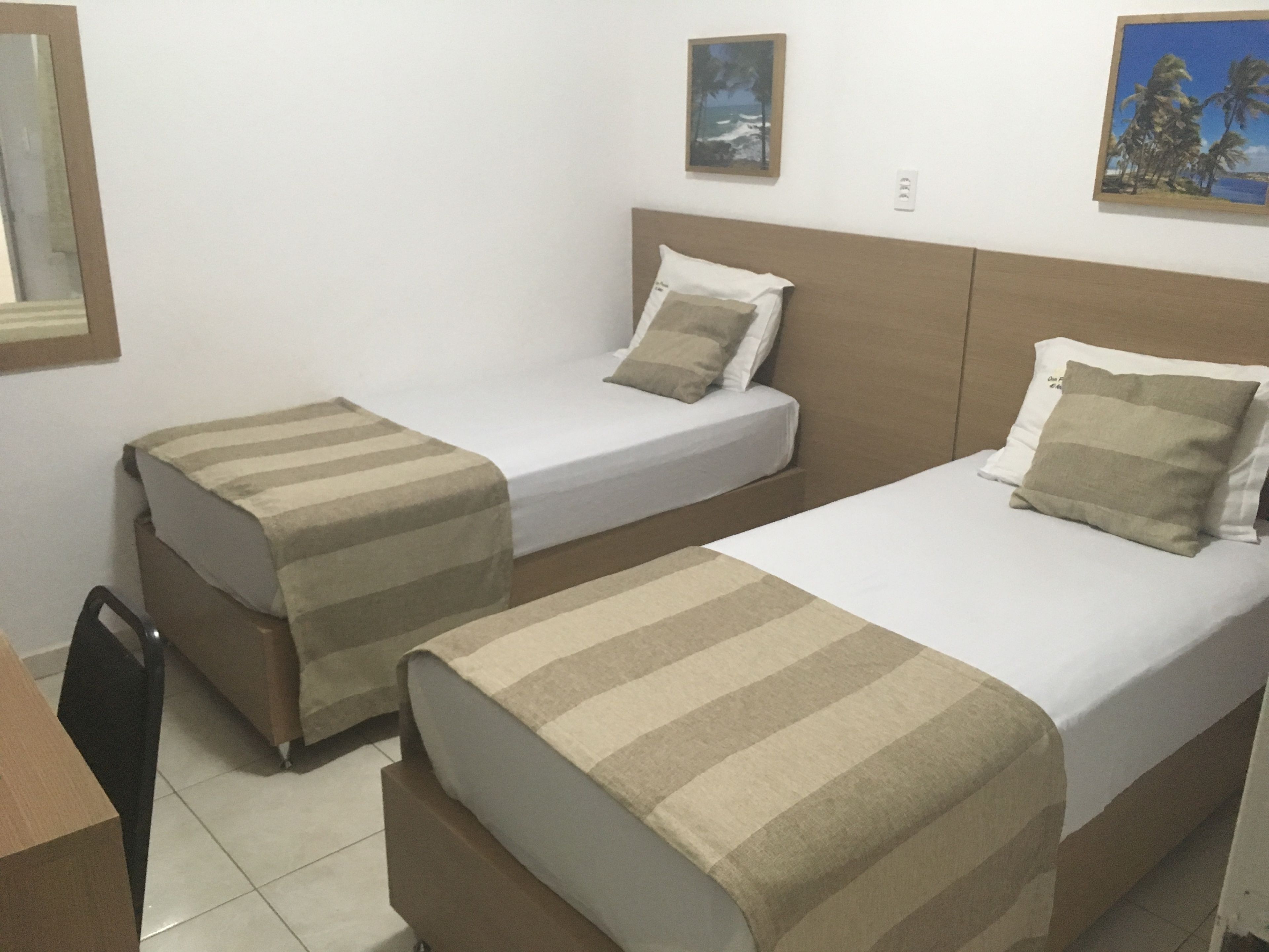 Quarto duplo com duas camas, uma escrivaninha e uma cadeira.